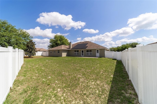 9896 SW 56th Ct, Ocala, FL 34476 - rear view of property with a yard, a fenced backyard, stucco siding, and solar panels