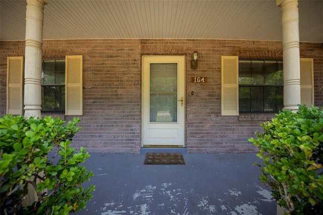 doorway to property with brick siding and a porch
