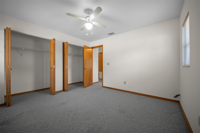unfurnished bedroom with multiple closets, baseboards, carpet flooring, and a ceiling fan