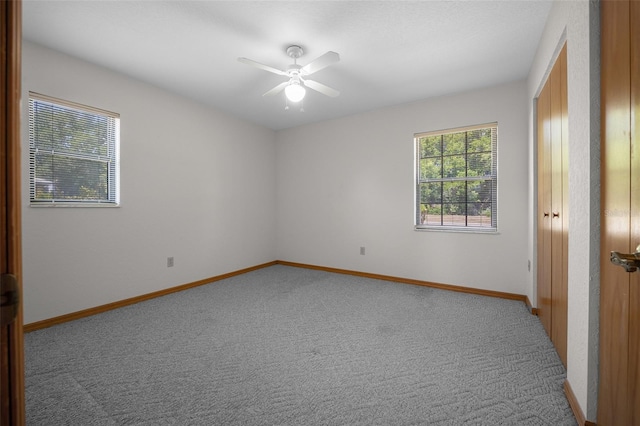 empty room featuring light carpet, a ceiling fan, and baseboards