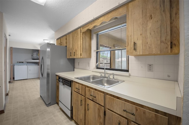 kitchen featuring dishwasher, washer and dryer, a sink, light countertops, and light flooring