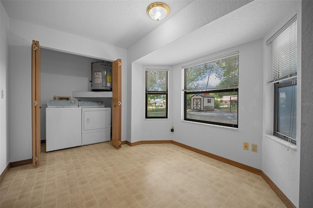 laundry room with washing machine and dryer, baseboards, light flooring, and a textured ceiling