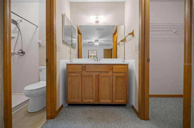 bathroom with ceiling fan, toilet, vanity, baseboards, and a shower