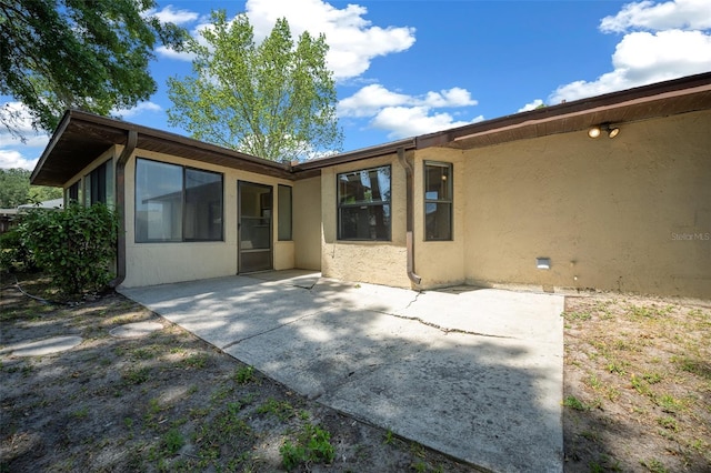 back of house featuring stucco siding and a patio area