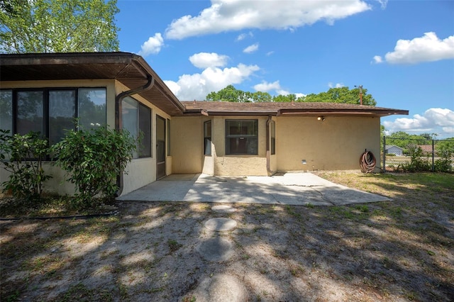 rear view of property featuring stucco siding, a patio area, and fence