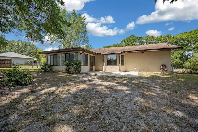 back of property featuring fence, a sunroom, stucco siding, and a patio area
