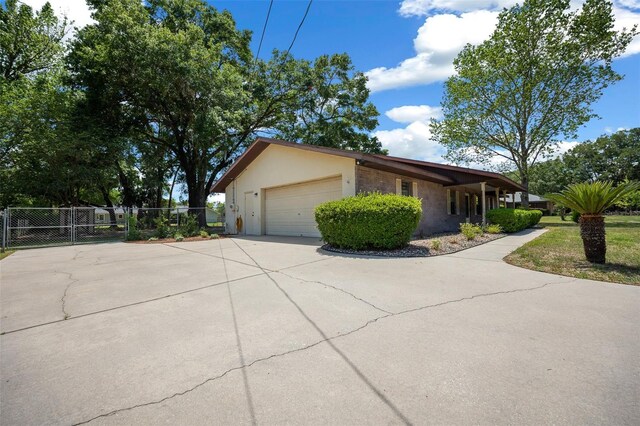 view of property exterior with driveway, fence, a garage, and stucco siding