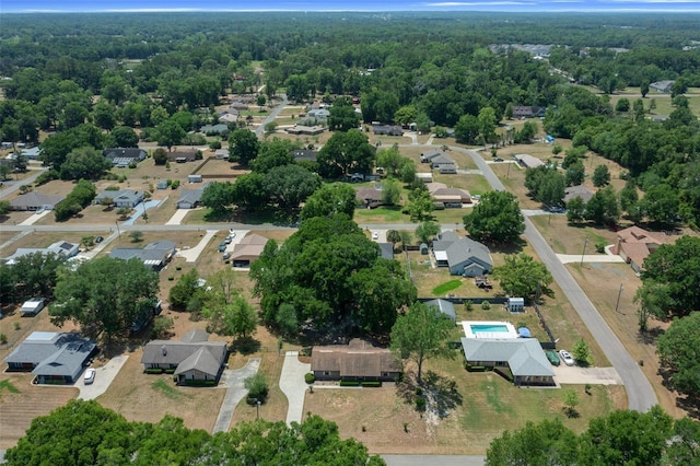 aerial view of property and surrounding area featuring nearby suburban area and a heavily wooded area