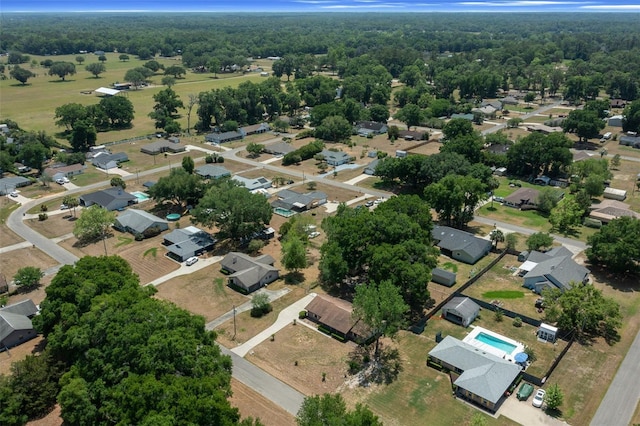 aerial view of property and surrounding area featuring nearby suburban area and a forest