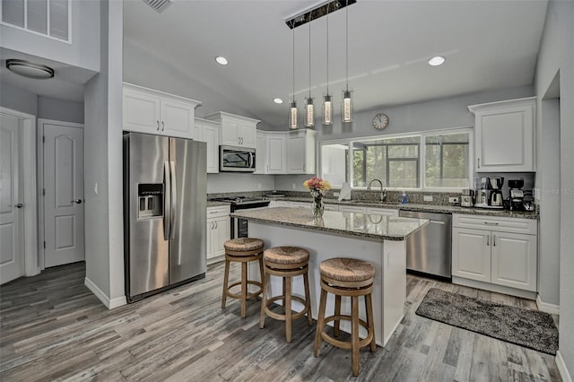 7407 SW 202nd Ct, Dunnellon, FL 34431 - kitchen with appliances with stainless steel finishes, white cabinets, light wood finished floors, light stone countertops, and vaulted ceiling