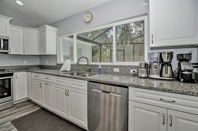 7407 SW 202nd Ct, Dunnellon, FL 34431 - kitchen with stainless steel appliances, white cabinets, stone countertops, dark wood-style floors, and lofted ceiling