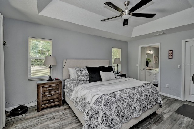 7407 SW 202nd Ct, Dunnellon, FL 34431 - bedroom featuring a tray ceiling, wood finished floors, ensuite bathroom, and ceiling fan