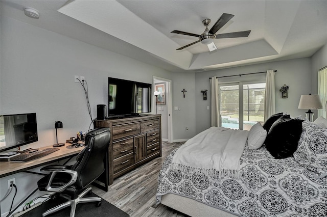 7407 SW 202nd Ct, Dunnellon, FL 34431 - bedroom featuring a tray ceiling, access to exterior, light wood finished floors, a desk, and ceiling fan