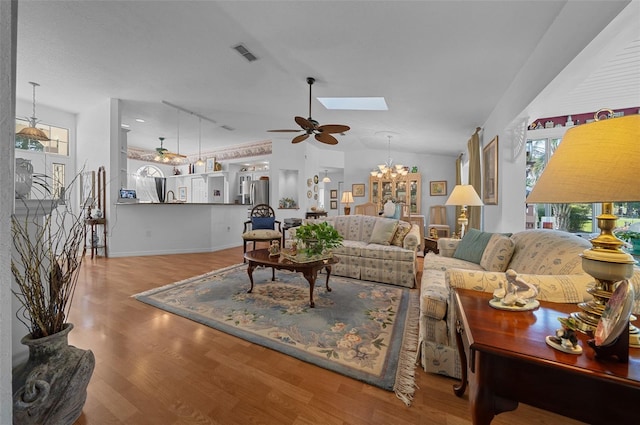 7692 SW 117th Street Rd, Ocala, FL 34476 - living room with visible vents, baseboards, lofted ceiling with skylight, wood finished floors, and ceiling fan with notable chandelier