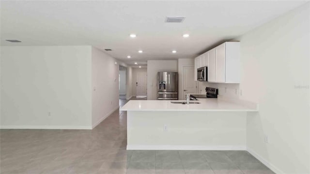kitchen with white cabinets, appliances with stainless steel finishes, a sink, light countertops, and visible vents