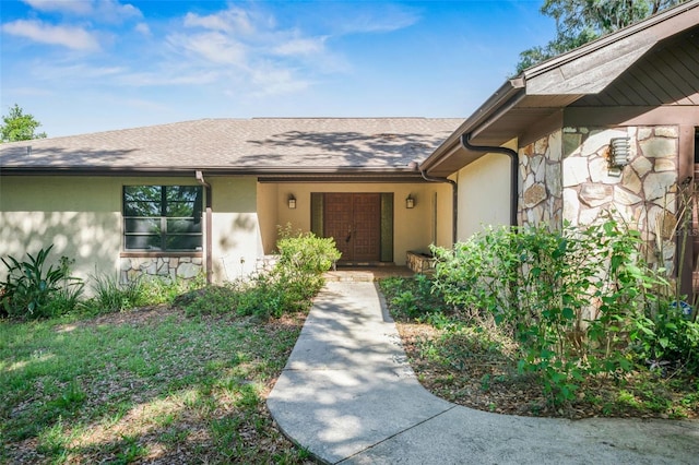 4401 E Windmill Dr, Inverness, FL 34453 - entrance to property featuring a shingled roof, stucco siding, and stone siding