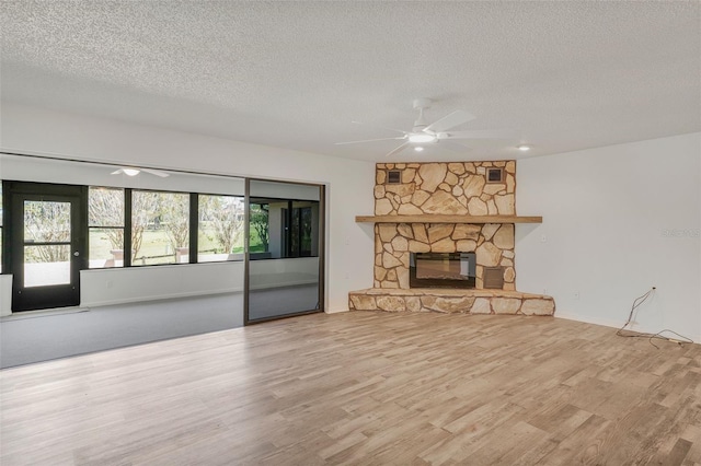 4401 E Windmill Dr, Inverness, FL 34453 - unfurnished living room featuring a stone fireplace, ceiling fan, wood finished floors, and a textured ceiling