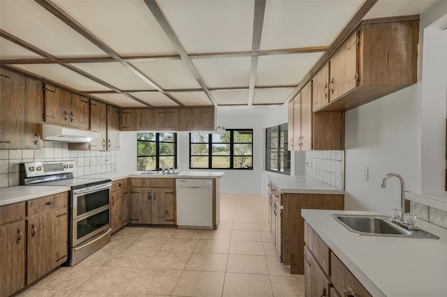 4401 E Windmill Dr, Inverness, FL 34453 - kitchen with backsplash, under cabinet range hood, white dishwasher, range with two ovens, and a sink