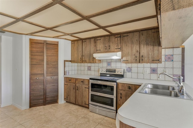 4401 E Windmill Dr, Inverness, FL 34453 - kitchen with backsplash, under cabinet range hood, brown cabinets, range with two ovens, and a sink