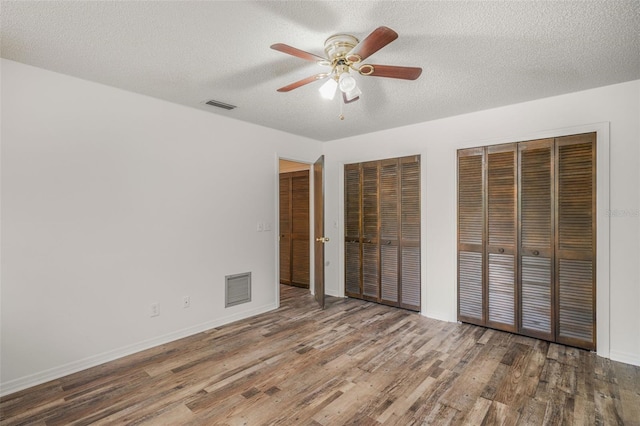 4401 E Windmill Dr, Inverness, FL 34453 - unfurnished bedroom featuring visible vents, a textured ceiling, multiple closets, and wood finished floors