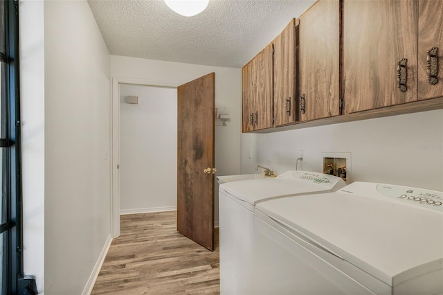 4401 E Windmill Dr, Inverness, FL 34453 - laundry area featuring light wood-style flooring, a textured ceiling, washing machine and clothes dryer, cabinet space, and a sink