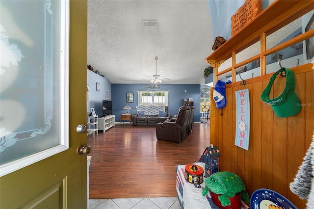interior space featuring tile patterned floors, ceiling fan, visible vents, and a textured ceiling