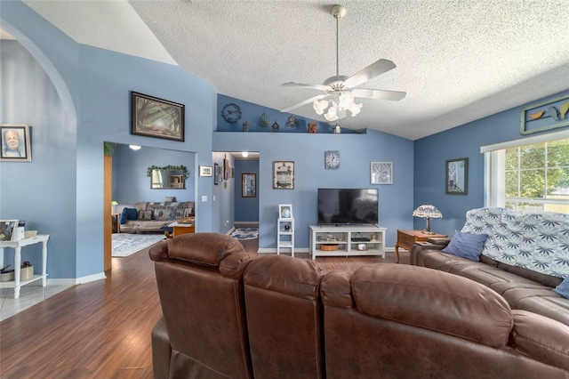 living room featuring dark wood-style flooring, vaulted ceiling, a textured ceiling, ceiling fan, and arched walkways