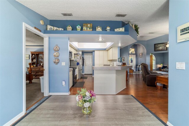 kitchen featuring open floor plan, dark wood-type flooring, visible vents, and a textured ceiling