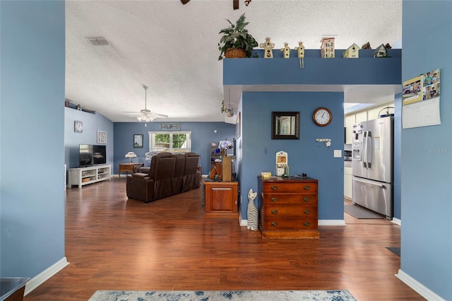 living room with visible vents, baseboards, a ceiling fan, a textured ceiling, and wood finished floors