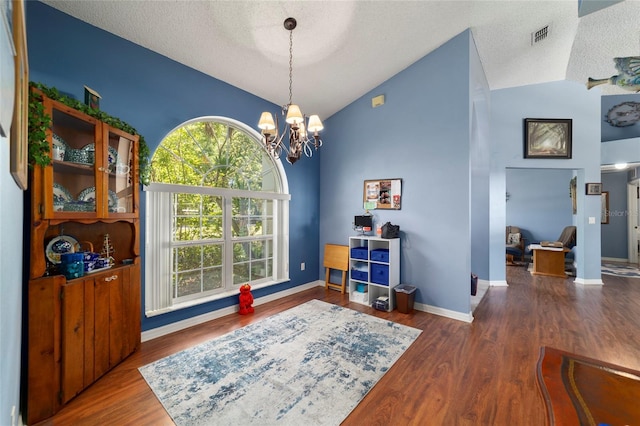 dining room featuring a textured ceiling, wood finished floors, a notable chandelier, and lofted ceiling