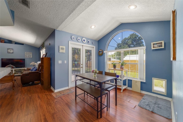 dining room with a textured ceiling, wood finished floors, visible vents, and lofted ceiling