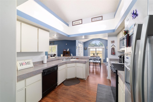 kitchen featuring open floor plan, a peninsula, white cabinetry, dark wood finished floors, and black appliances