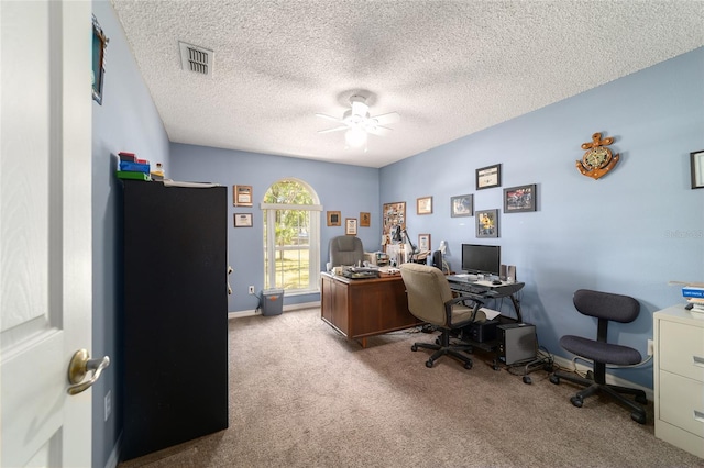 carpeted home office with visible vents, ceiling fan, baseboards, and a textured ceiling
