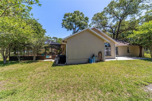 rear view of house with a patio area, a yard, a lanai, and stucco siding