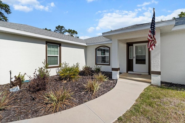 property entrance featuring stucco siding and a shingled roof
