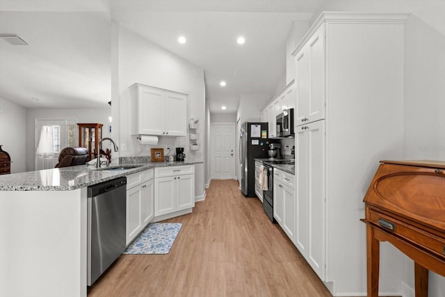 kitchen featuring a sink, stainless steel appliances, light wood-style flooring, white cabinets, and a peninsula