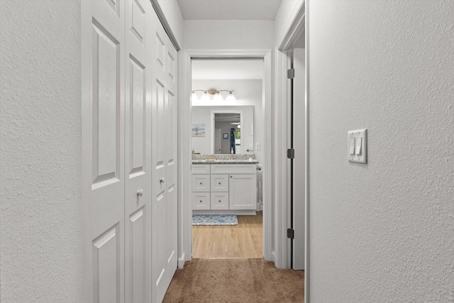 hallway featuring a textured wall and dark carpet