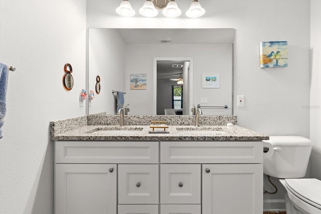 bathroom with ceiling fan, toilet, a sink, and double vanity