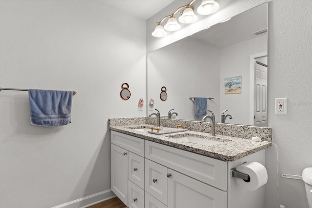 bathroom featuring visible vents, a sink, double vanity, and toilet