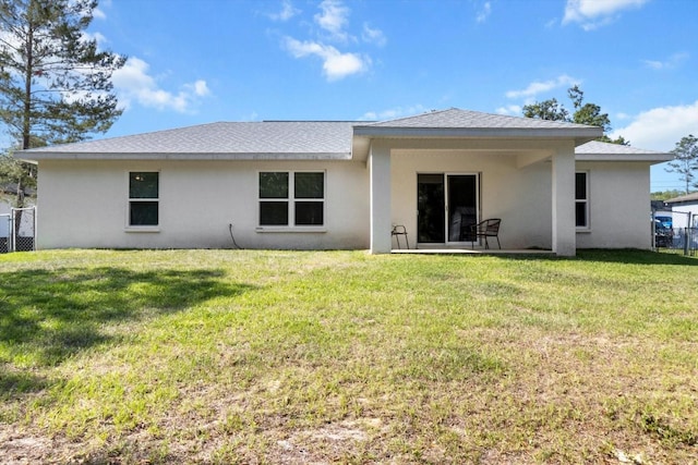 back of house featuring stucco siding, fence, and a lawn
