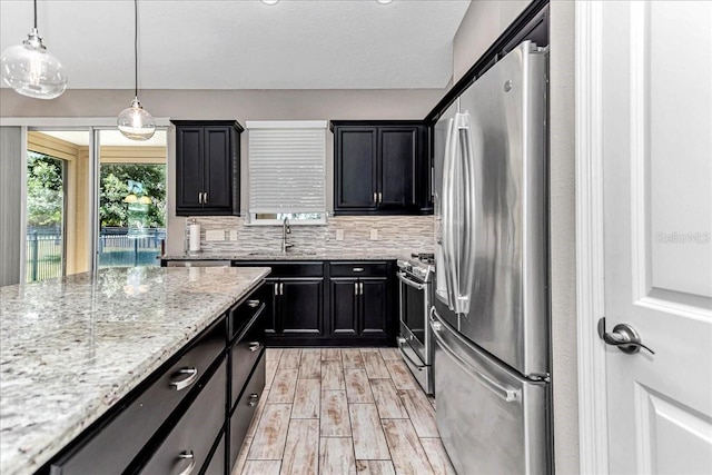 3918 NW 46th Ter, Ocala, FL 34482 - kitchen featuring light wood finished floors, light stone countertops, a sink, dark cabinetry, and appliances with stainless steel finishes