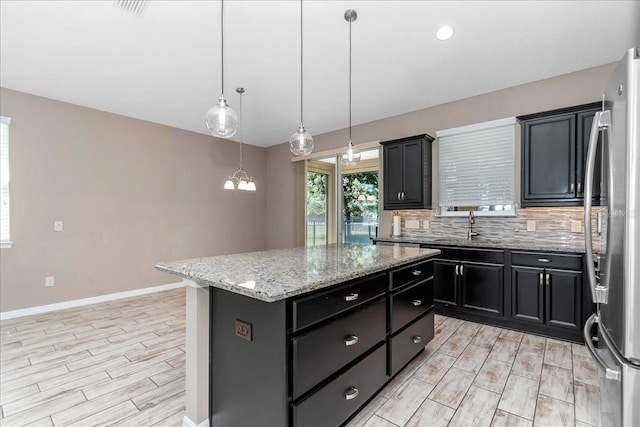 3918 NW 46th Ter, Ocala, FL 34482 - kitchen with wood tiled floor, dark cabinets, backsplash, and freestanding refrigerator