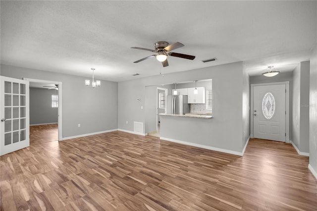 15044 SW 35th Avenue Rd, Ocala, FL 34473 - unfurnished living room with ceiling fan with notable chandelier, wood finished floors, baseboards, and visible vents
