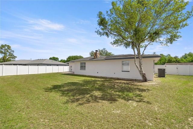 15044 SW 35th Avenue Rd, Ocala, FL 34473 - rear view of house with a fenced backyard, a chimney, a lawn, and central air condition unit