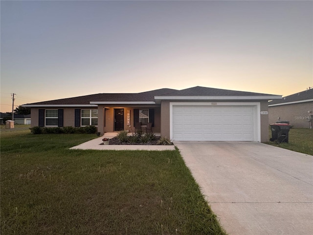 view of front of home with a garage, a front yard, concrete driveway, and stucco siding