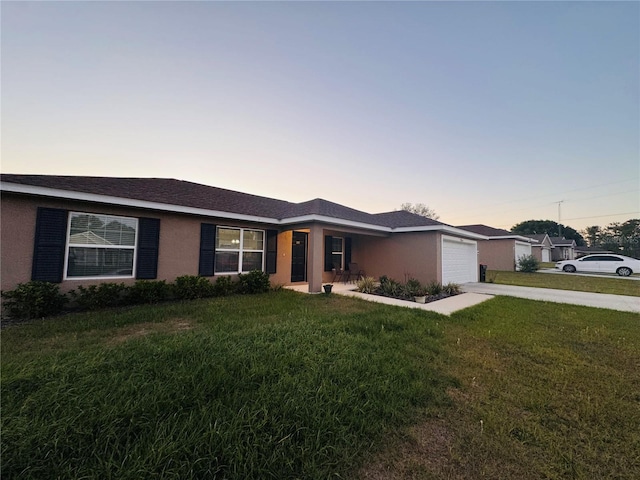 single story home with a garage, a yard, stucco siding, and concrete driveway