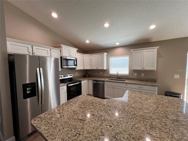 kitchen with light stone counters, a textured ceiling, a sink, stainless steel appliances, and white cabinets