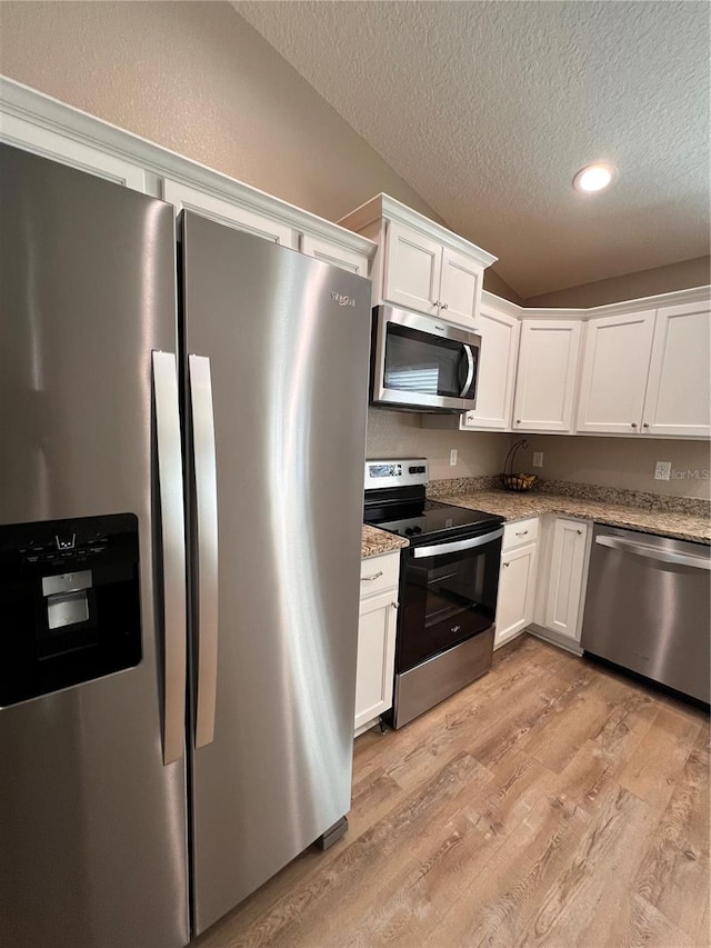 kitchen with white cabinets, light stone counters, stainless steel appliances, light wood-style flooring, and a textured ceiling