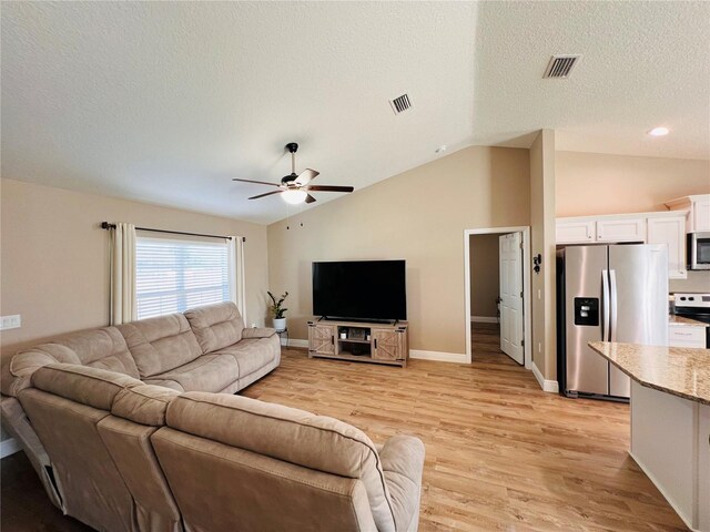 living area with light wood-type flooring, lofted ceiling, visible vents, and ceiling fan