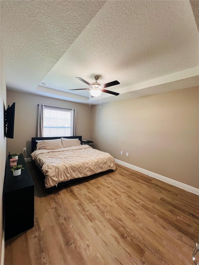 bedroom featuring baseboards, wood finished floors, and a textured ceiling